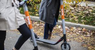 Dos personas circulan con el patinete eléctrico Spin por una acera